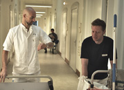 Portør og rengøringsassistent går på hospitalsgang