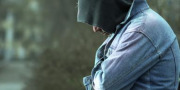 Ung mand bøjer hovedet, tildækket af sin hætte