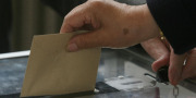 En hånd lægger en stemmeseddel i en boks