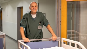 Bag hospitalssengen står Flemming Ettrup Christensen – portøren, der har gjort forskellen med nærvær, erfaring og stille styrke.