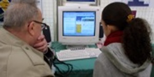 Ældre mand sidder med ung kvinde foran computer